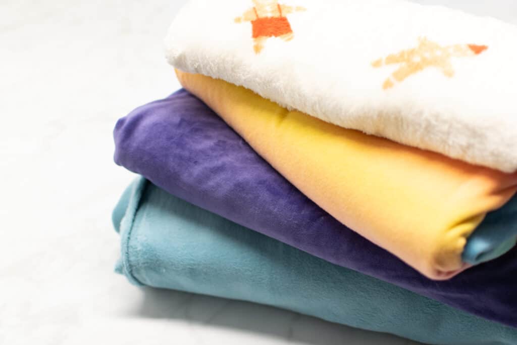 a stack of four different fleece fabrics on a white background