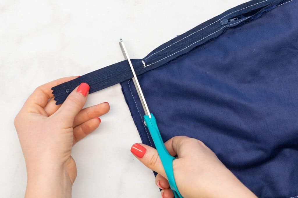 trimming away the excess zipper with turquoise scissors
