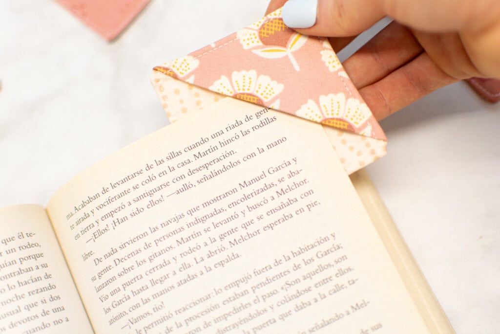 closeup of placing a corner fabric bookmark on the page of a book